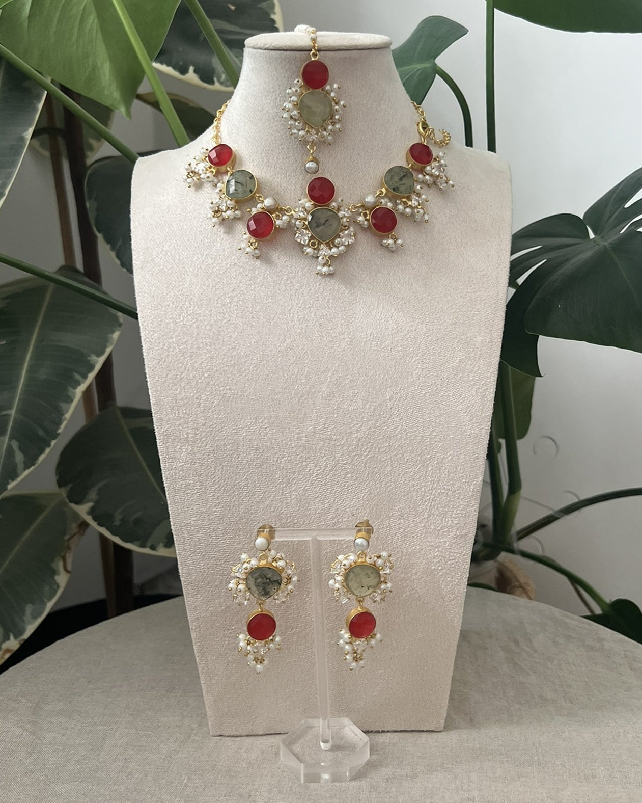 Jewelry set on a mannequin bust with green leaves in the background