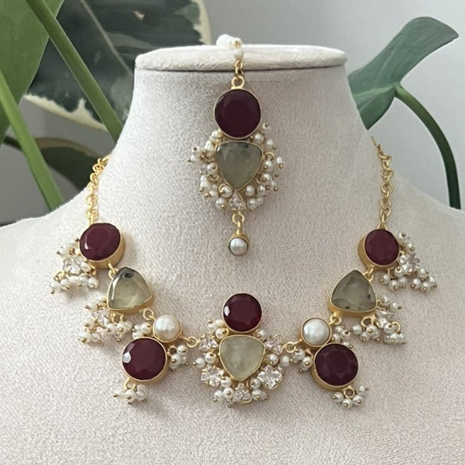 Jewelry set on a white stand with green plants in the background