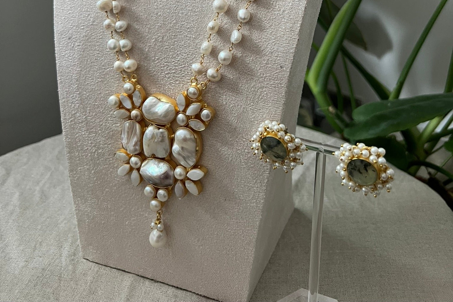 Indian imitation jewellery set with mala pearl gold necklace, mother of pearl and prehnite green round earrings surrounded by pearl clusters.