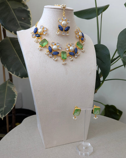 Jewelry set on a white stand with green leaves in the background