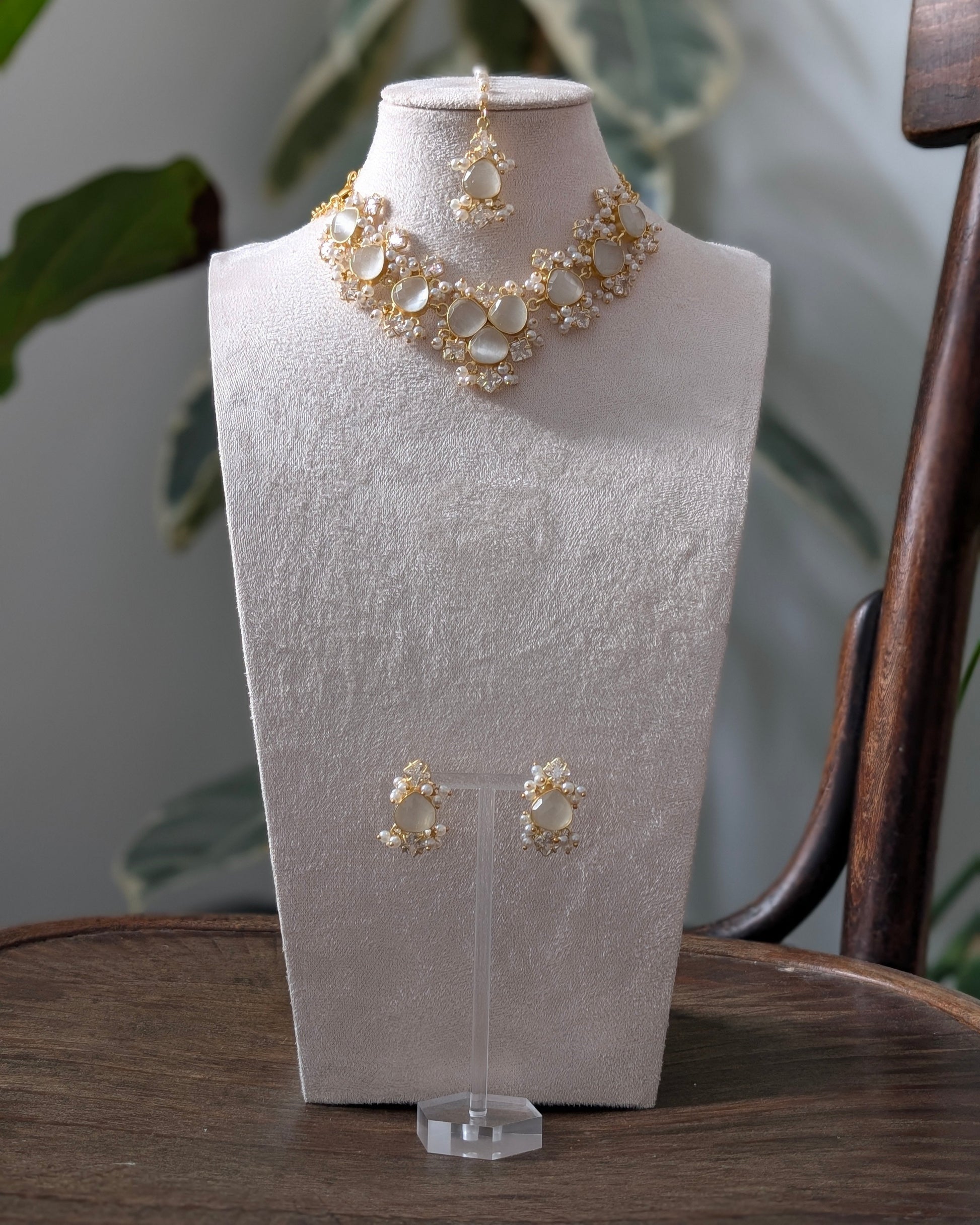 Gold necklace and earrings on a white mannequin bust with a natural background