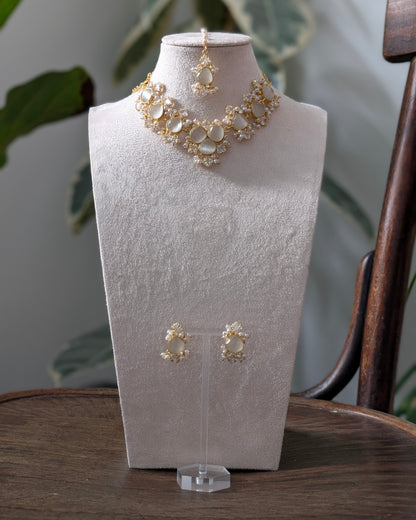 Gold necklace and earrings on a white mannequin bust with a natural background