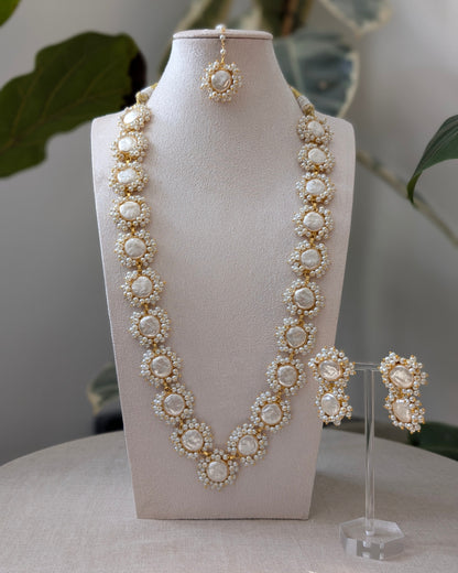 Pearl necklace and earrings set on a mannequin bust with a soft background