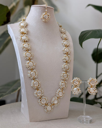 Pearl necklace and earrings on a mannequin bust with a blurred plant background