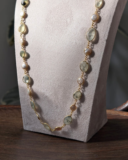 Necklace with green and gold beads on a white stand