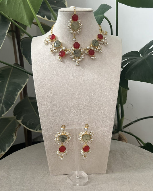 Jewelry set on a mannequin bust with green leaves in the background