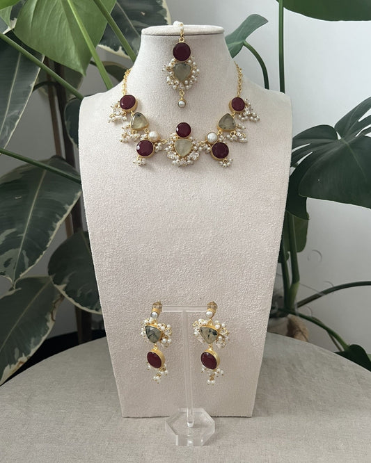 Jewelry set on a white stand with green plants in the background