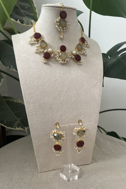 Jewelry set on a white stand with a plant in the background