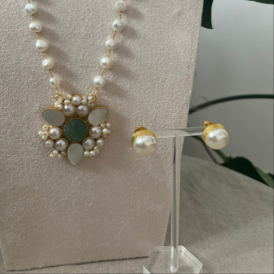 Pearl necklace and earrings on a mannequin bust with a neutral background