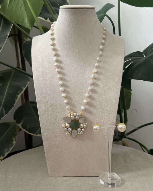 Pearl necklace on a mannequin bust with a plant in the background