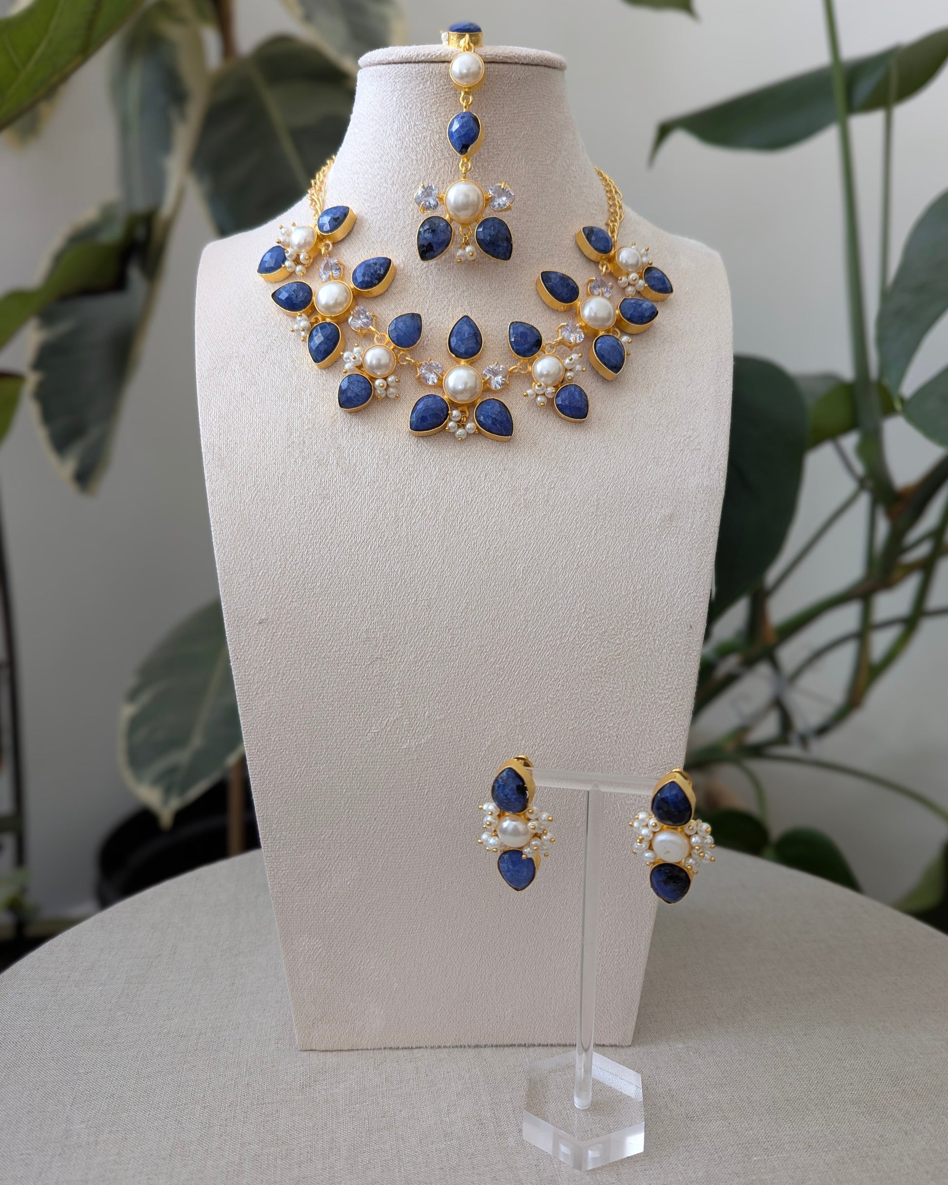 Jewelry set with necklace and earrings on a mannequin bust against a natural background