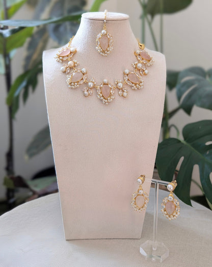 Gold and pearl jewelry set on a mannequin bust with green foliage in the background