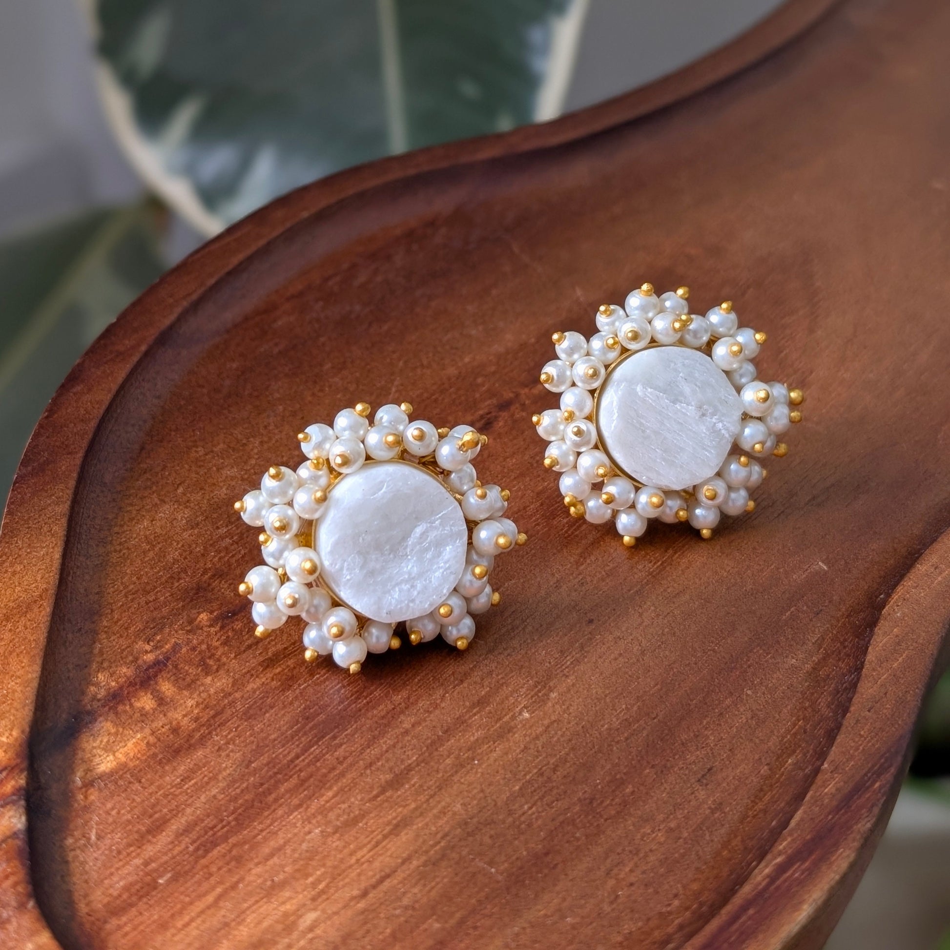 Pair of earrings with pearl-like stones on a wooden surface