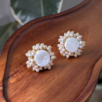 Pair of earrings with pearl-like stones on a wooden surface