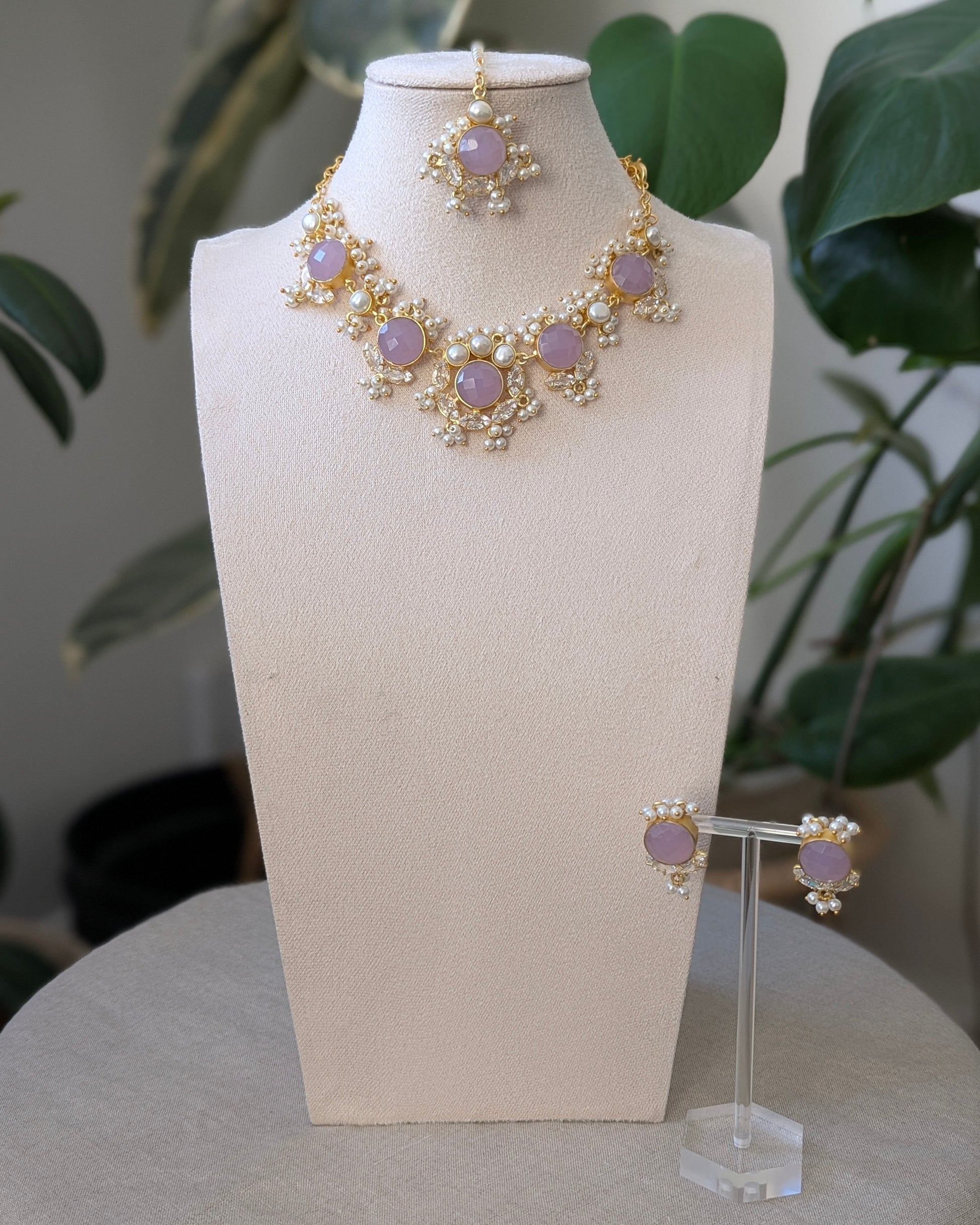 Jewelry set on a mannequin bust with a plant in the background