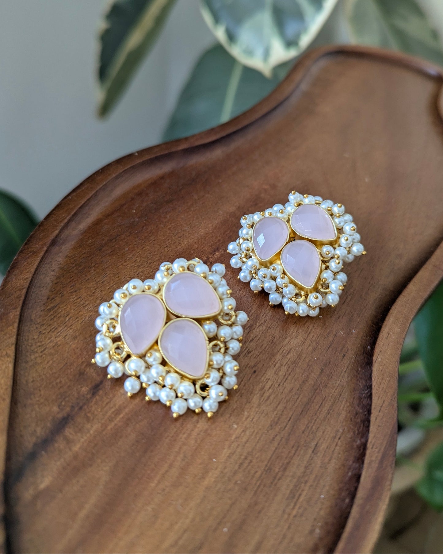 Pair of earrings with pink stones and gold accents on a wooden surface.