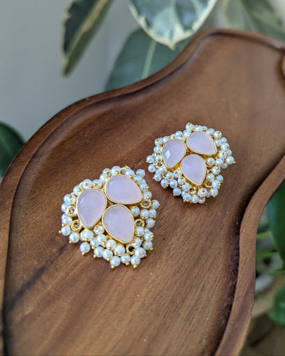 Pair of earrings with pink stones and gold accents on a wooden surface.