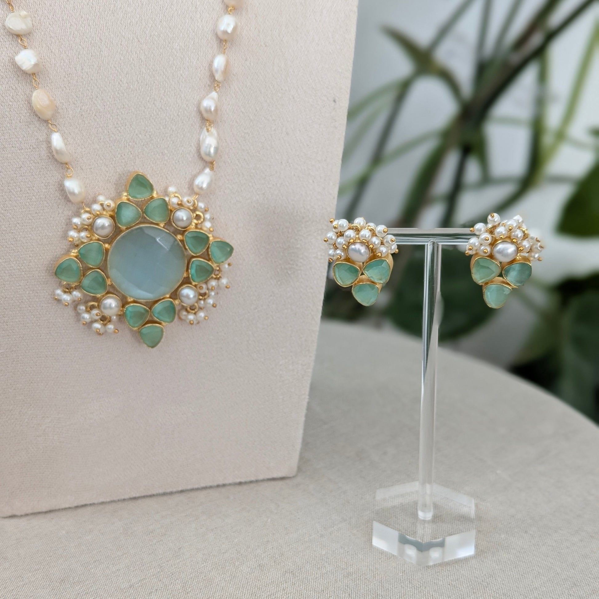 Jewelry set with necklace and earrings on a stand against a neutral background