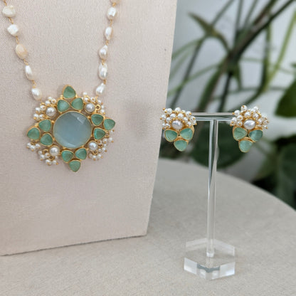 Jewelry set with necklace and earrings on a stand against a neutral background