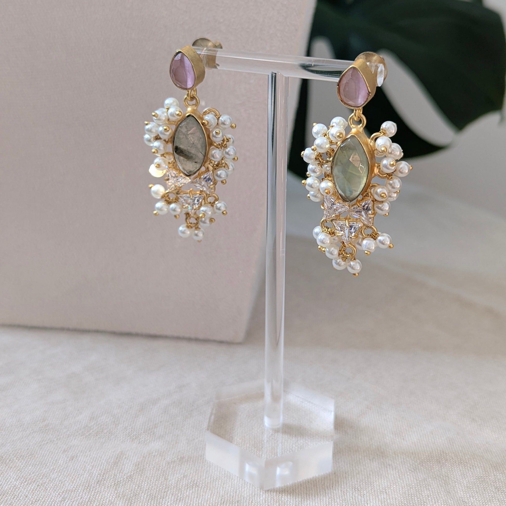 Pair of earrings on a clear stand with a neutral background