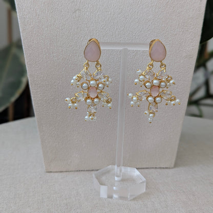 Pair of earrings on a clear stand with a neutral background
