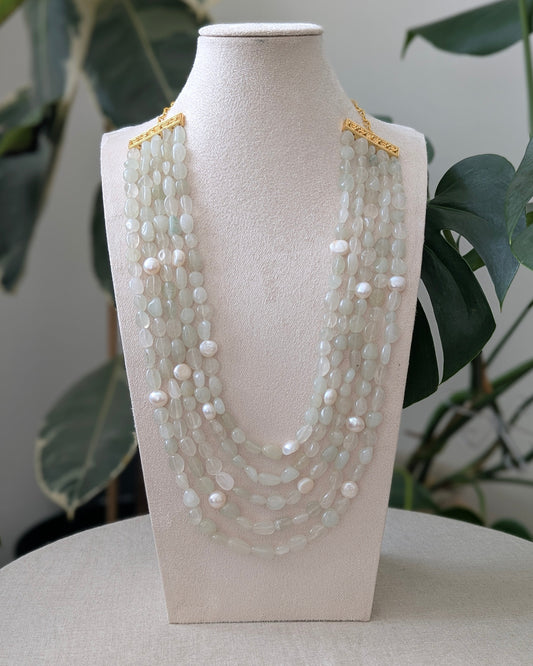 Necklace displayed on a mannequin bust with a plant in the background