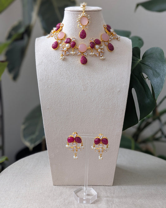 Jewelry set with pink and gold accents on a mannequin bust.