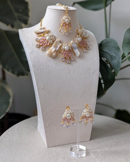 Jewelry set including necklace and earrings on a mannequin bust with plants in the background