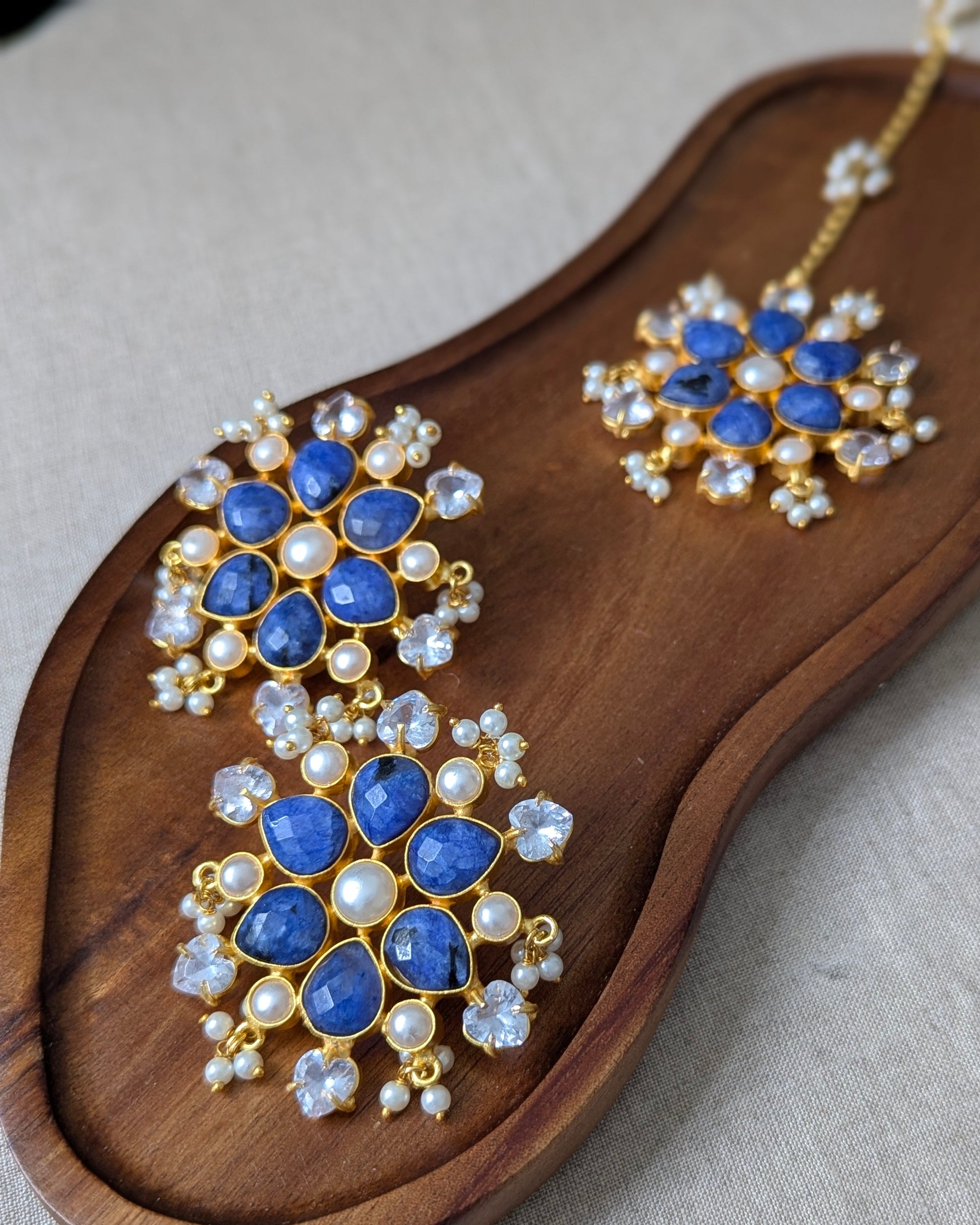 Pair of blue gemstone earrings on a wooden tray