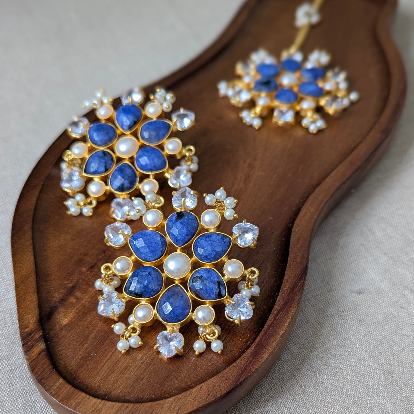 Pair of blue gemstone earrings on a wooden tray