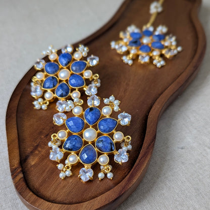 Pair of blue gemstone earrings on a wooden tray