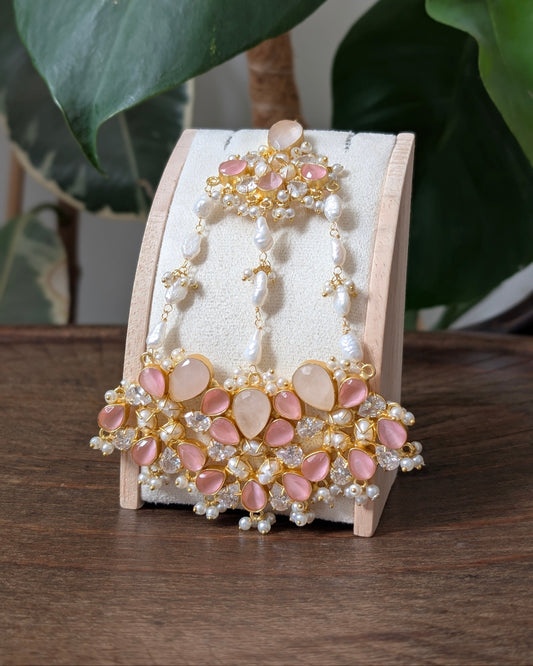 An ornate gold-toned traditional Chinese style hairpin (juejin) decorated with pink stones and white pearls, displayed on a wooden stand.