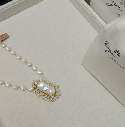 Pearl necklace on a branded jewelry box with 'Roya' bags